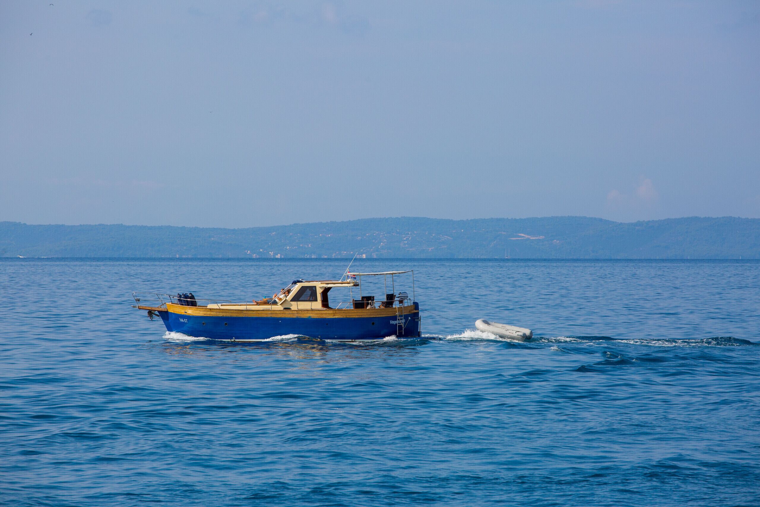 A boat on calm water with a distant shoreline.