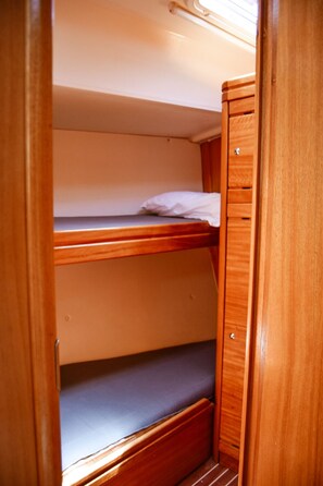 Una cama litera con una cama inferior y una superior, ambas con estructura de madera y un colchón en la cama superior.