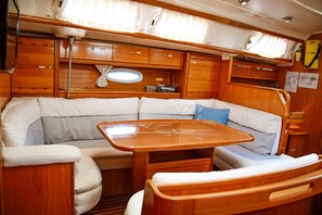 Un interior acogedor y bien iluminado, con diseño de madera, que incluye una zona de estar con cojines, una mesita pequeña y armarios de almacenamiento.