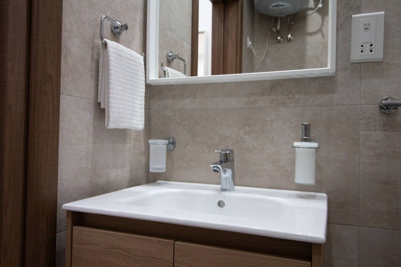 A bathroom with a white sink, a mirror, a towel rack, and a shower head.