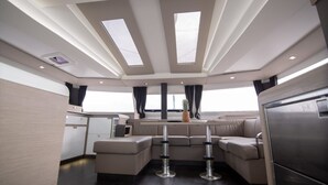 A modern interior with a dining area, a kitchen, and a seating area with a view of the sky. - Sun-Kissed Sailing Adventure in Islas Cícladas, Mykonos (Mykonos)