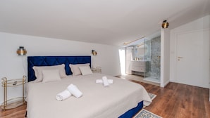 Un dormitorio con cama, mesita de noche, baño con ducha y puerta.
