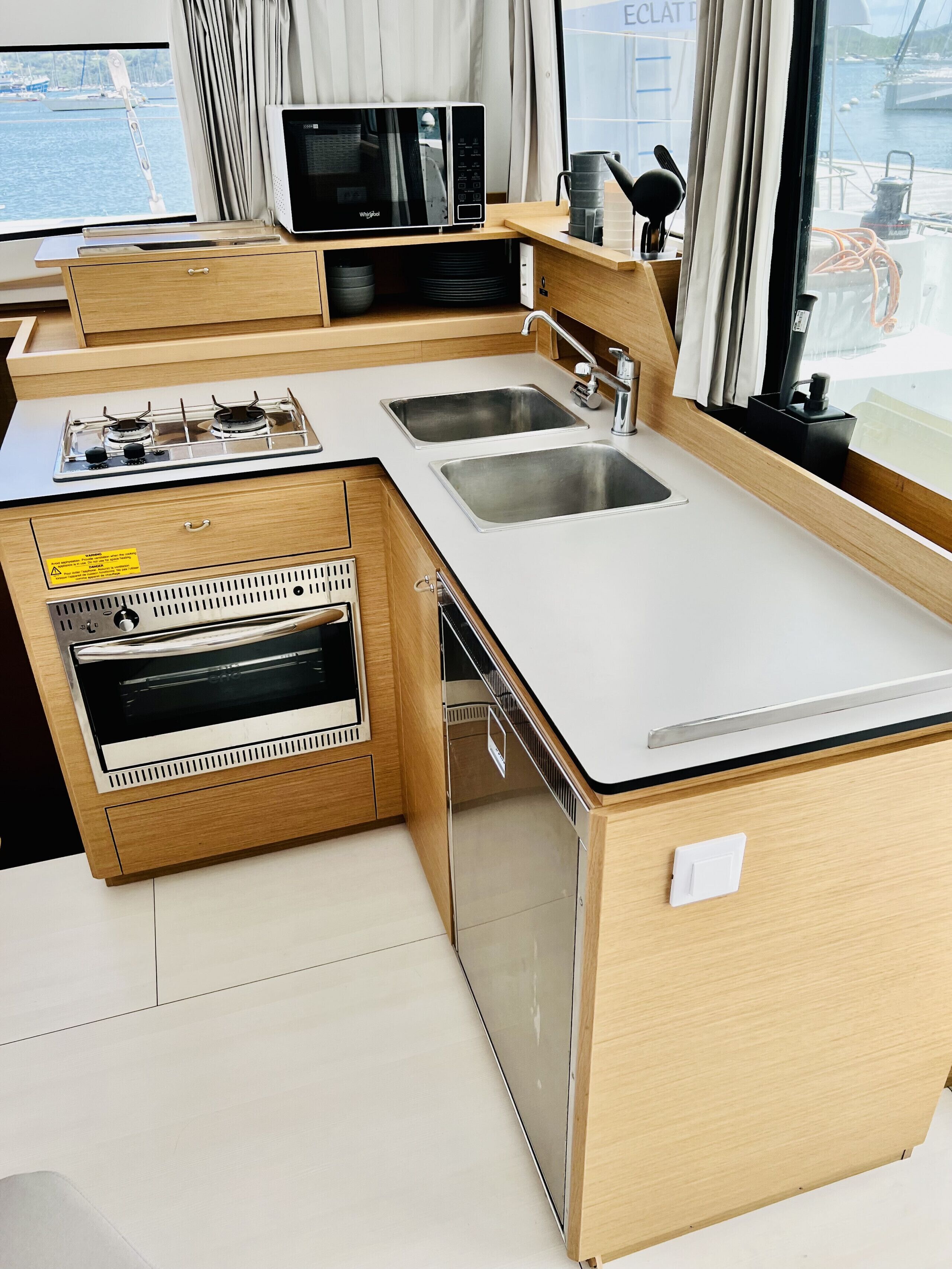 Een kleine keuken met een magnetron, fornuis, spoelbak en vaatwasser.