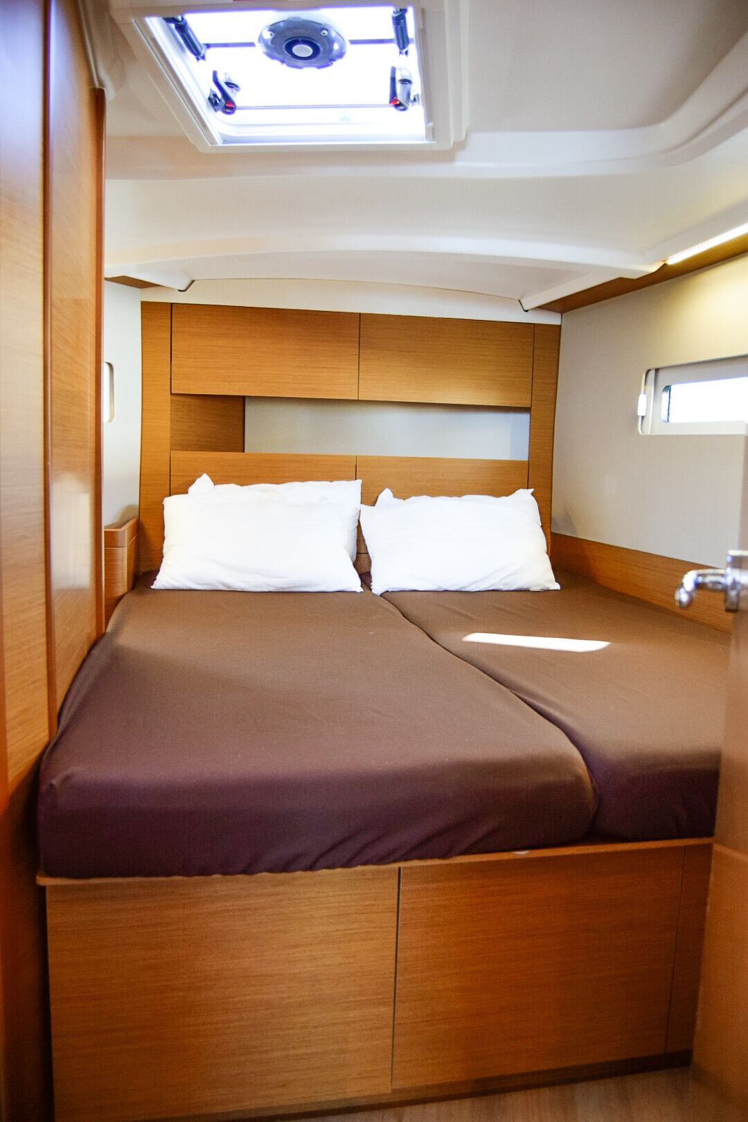 Ein gemütliches Schlafzimmer mit Dachfenster, zwei Betten und einem hölzernen Kopfende.
