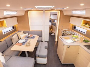 A compact interior with a dining area, kitchenette, and seating. - Sun-Kissed Sailing Adventure in Islas Baleares, Mallorca (Palma)