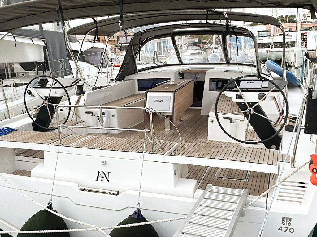 A boat deck with a steering wheel, a control panel, and a seating area.