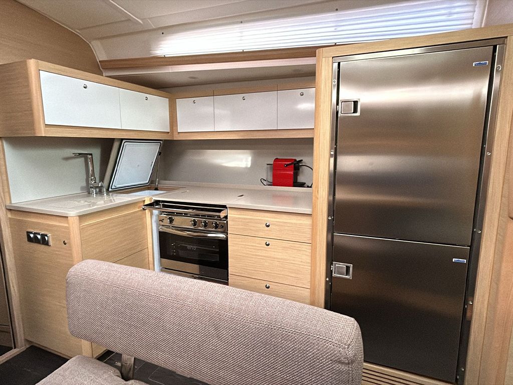 Una cocina compacta con estufa, horno y refrigerador, armarios de madera y un banco.