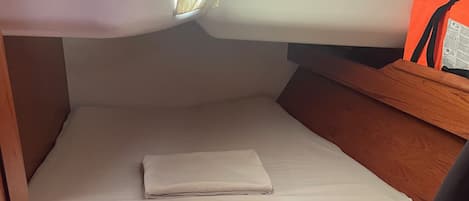A compact cabin with a single bed, a small table, and a bench.