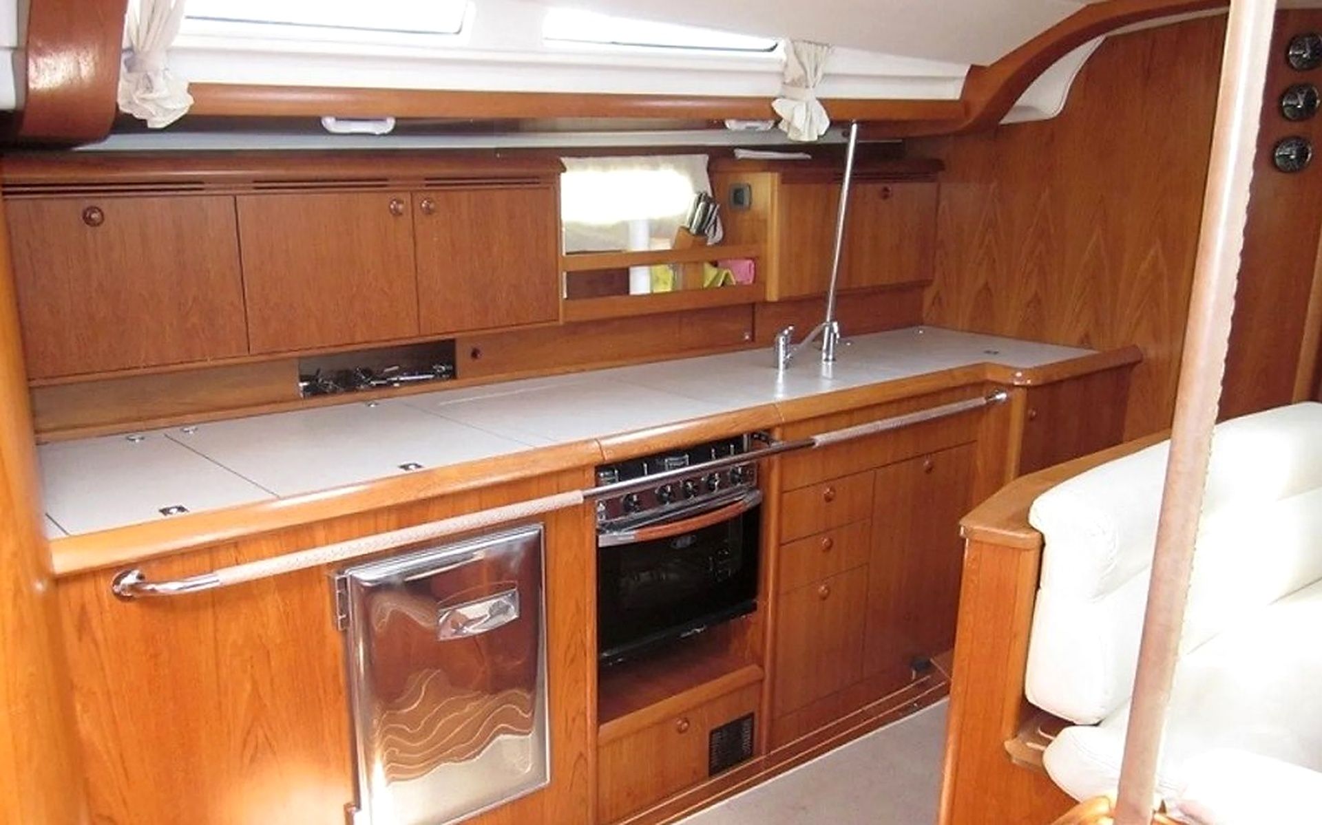 Una cocina compacta con armarios de madera, horno integrado y un refrigerador pequeño.