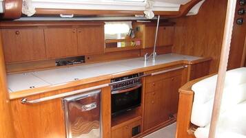 Una cocina compacta con armarios de madera, horno integrado y un refrigerador pequeño.