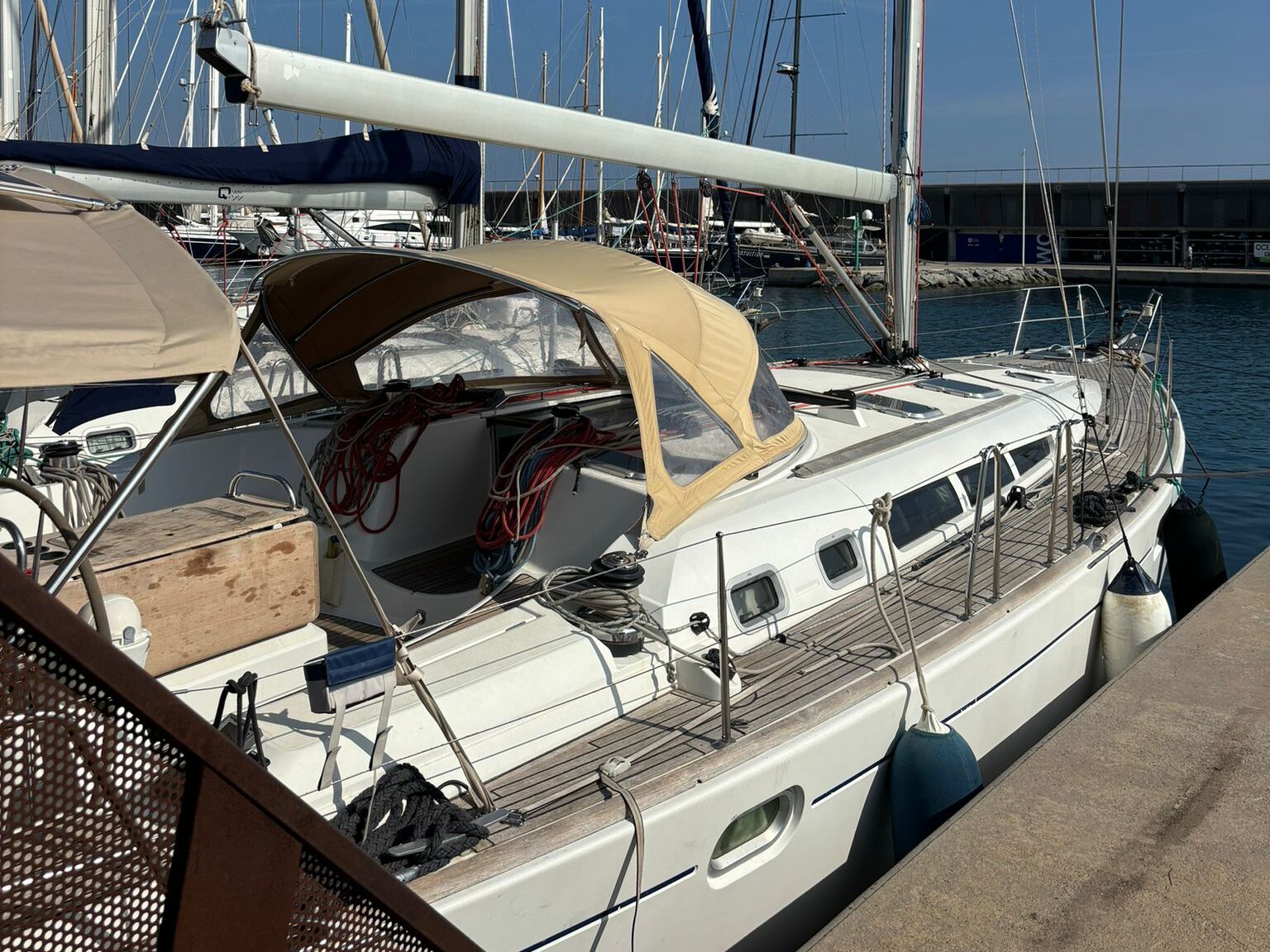 A sailboat docked at a marina with a covered deck area, a cabin with windows, and a small deck space.