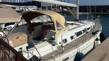 A sailboat docked at a marina with a covered deck area, a cabin with windows, and a small deck space.