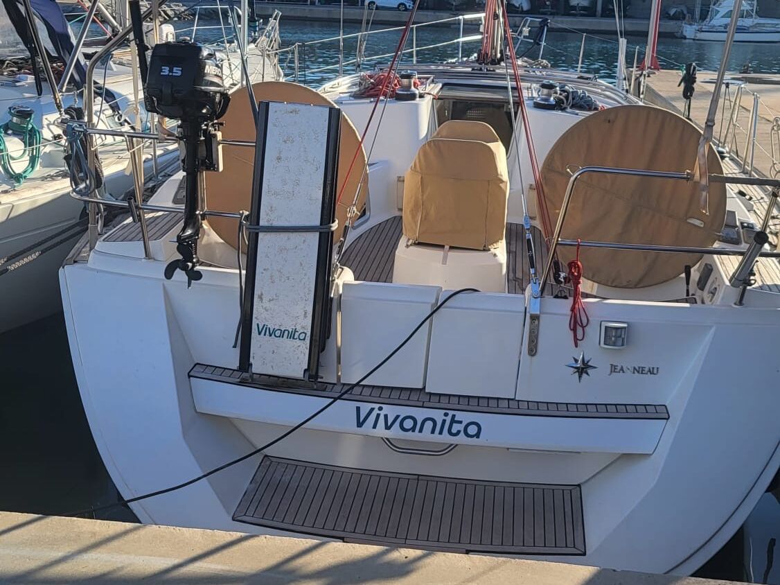 Un barco llamado 'Vivanita' atracado en una marina, equipado con un motor fueraborda de 3,5 caballos de fuerza, un timón y una zona de estar con toldo.