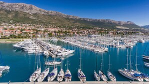 Un port de plaisance où sont amarrés de nombreux bateaux, une ville en arrière-plan et des montagnes.