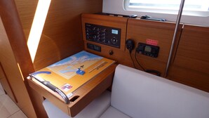 Un panneau de contrôle doté de divers boutons et d’une carte, une petite table avec une carte et un porte-clés, et une fenêtre donnant sur le ciel.