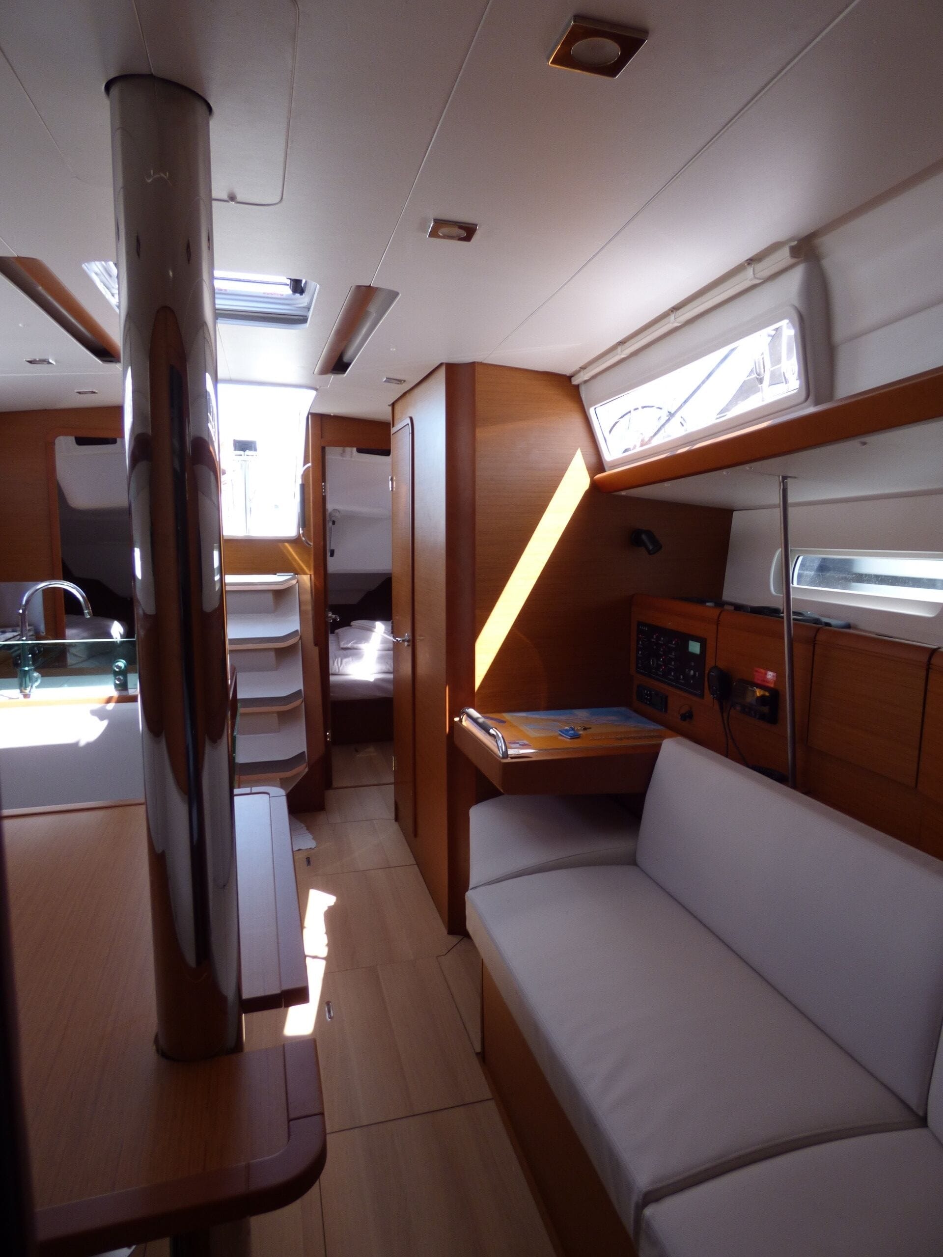 A compact interior with a bunk bed, a small desk, and a control panel, likely for a boat or RV.