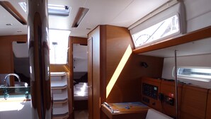 Un intérieur compact comprenant un lit superposé, un petit bureau et un panneau de commande, probablement pour un bateau ou un véhicule récréatif.