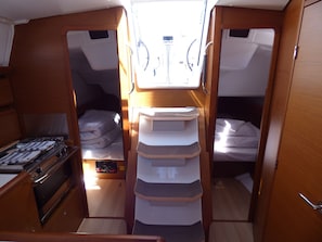 A compact interior with two beds, a kitchenette, and a central storage unit.