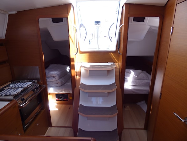 A compact interior with two beds, a kitchenette, and a central storage unit.