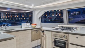 A modern kitchen with a built-in oven, a gas stove, and a large window overlooking a cityscape.