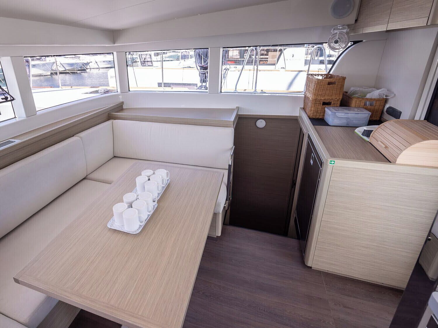 Une petite cuisine équipée comprenant un coin repas, un petit évier et une fenêtre donnant sur les bateaux.