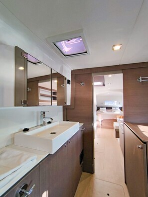 Een moderne badkamer met een grote spiegel, een wit wastafelmeubel en een douchehoek.