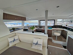 A yacht interior with a seating area, kitchen, and a view of the sea.