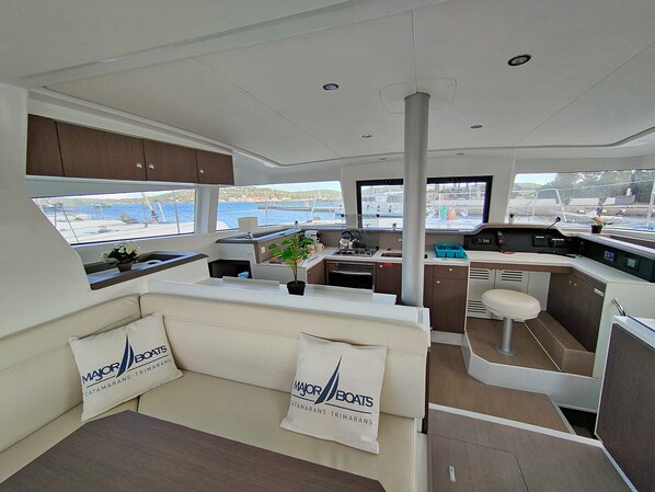 A yacht interior with a seating area, kitchen, and a view of the sea.