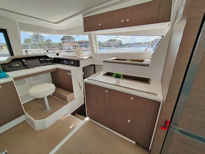 A compact kitchen with a central island, a small seating area, and a view of the marina.