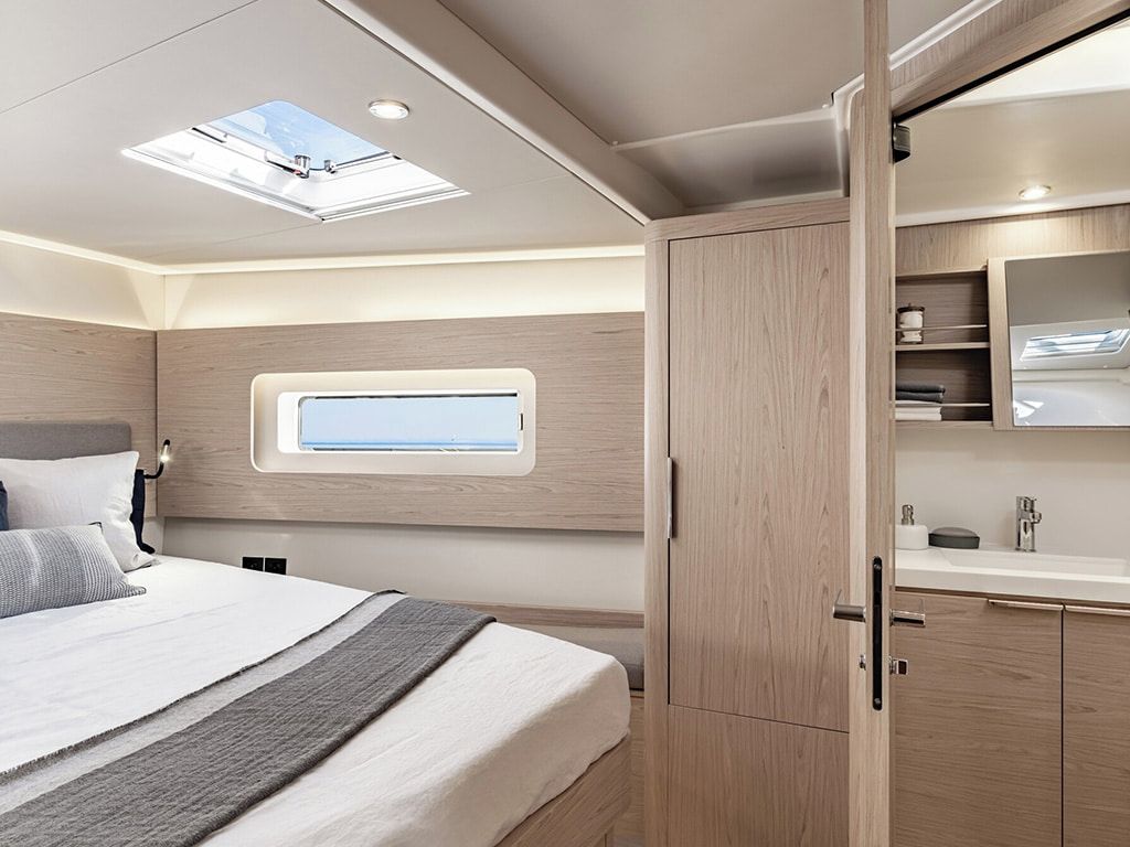 Een slaapkamer met dakraam, een bed met kussens, een nachtkastje en een houten kledingkast.