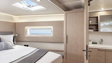 Een slaapkamer met dakraam, een bed met kussens, een nachtkastje en een houten kledingkast.