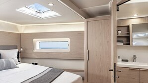 A bedroom with a skylight, a bed with pillows, a bedside table, and a wooden wardrobe. - Sun-Kissed Sailing Adventure in Islas Baleares, Mallorca (Palma)