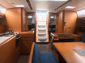 A compact kitchen with a stove, sink, and counter, a dining area with a table and chairs, and a small seating area with a bench.