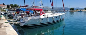 A sailboat docked at a marina with a clear view of the water and distant mountains.