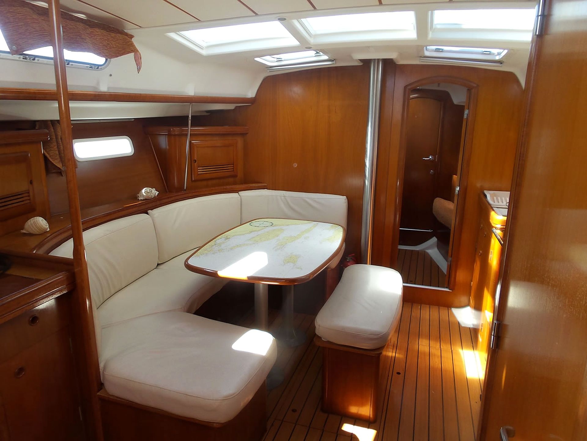 A compact interior with a cushioned seating area, a small table, and a door leading to another room.