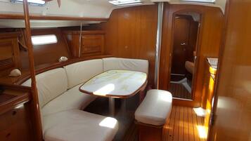 A compact interior with a cushioned seating area, a small table, and a door leading to another room.
