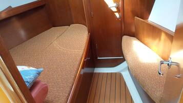 A compact cabin with a single bed, a small seating area, and a built-in sink.