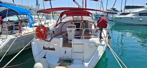 A sailboat docked at a marina with a cabin, a steering wheel, and a lifebuoy.