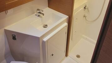 A compact bathroom with a white sink, mirror, and shower.