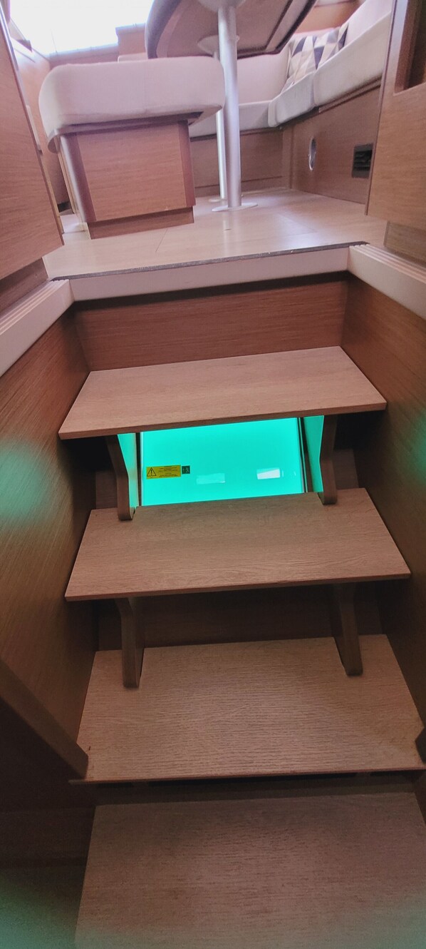 A wooden staircase with a green-lit compartment at the bottom.