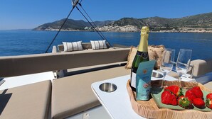 Een scheepdek met een fles champagne, glaasjes en aardbeien op een schaal.