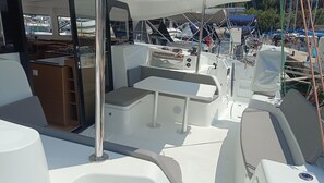 Interior de un barco con zona de estar, una mesa y panel de control.