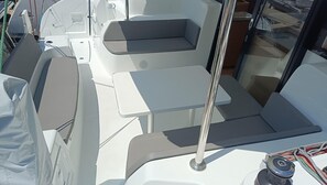 A boat's interior with a seating area, a table, and a window.