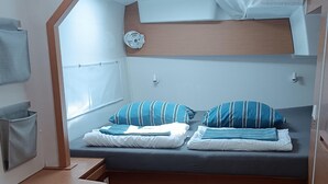 Une cabine compacte comprenant un lit superposé, un petit bureau et un meuble de rangement.