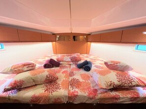 Ein Bett mit floralem Muster, Kissen und gefalteten Handtüchern.