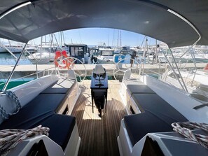 Ein Bootsdeck mit Sitzgelegenheiten, einem Steuer und Blick auf andere Boote in einer Marina.