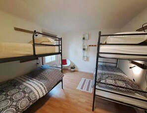 A dormitory room with bunk beds, a small table, a chair, and a window. - Nature Base Near Fishing Waters (Heinkenszand)
