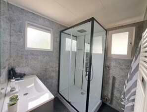 A modern bathroom with a glass shower enclosure, a white sink, and a radiator. - Nature Base Near Fishing Waters (Heinkenszand)