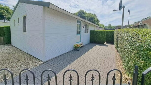 A white single-story house with a paved driveway and a metal fence in the foreground. - Nature Base Near Fishing Waters (Heinkenszand)