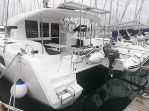 A white yacht docked at a marina with a small enclosed deck area, a table, and a Yamaha outboard motor.